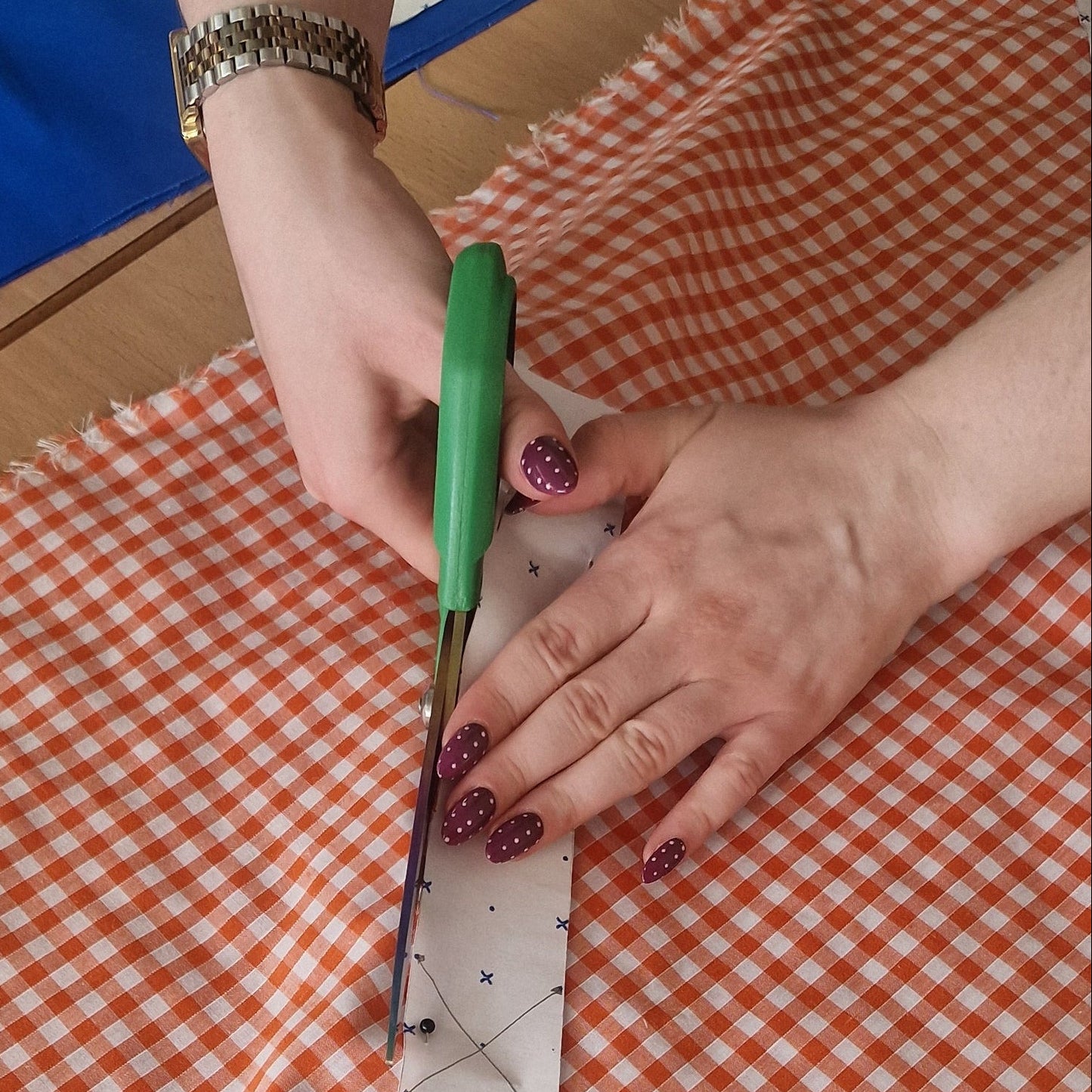 Person measuring fabric with a ruler on a checkered tablecloth