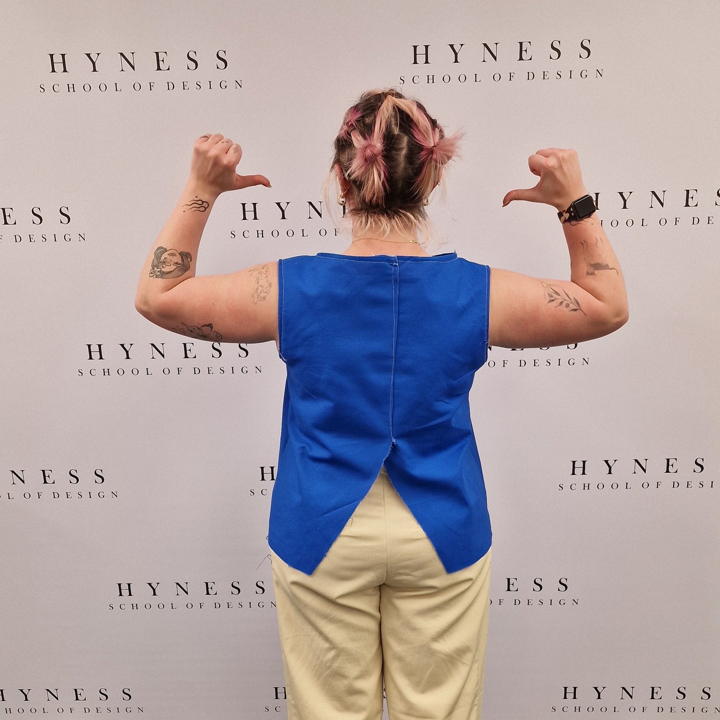 Person wearing a blue top and beige pants standing on a large book titled 'Hyness'.