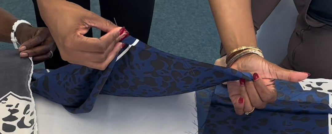 Person holding blue fabric with black pattern on a table with candles and papers.