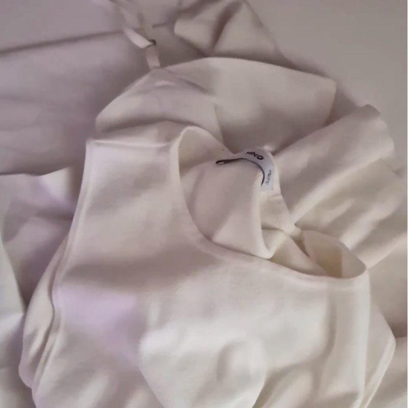 Close-up of a white hoodie with a brand tag on a light gray background