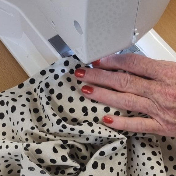Milton Keynes Sewing Class Person using a sewing machine with polka dot fabric on a wooden table