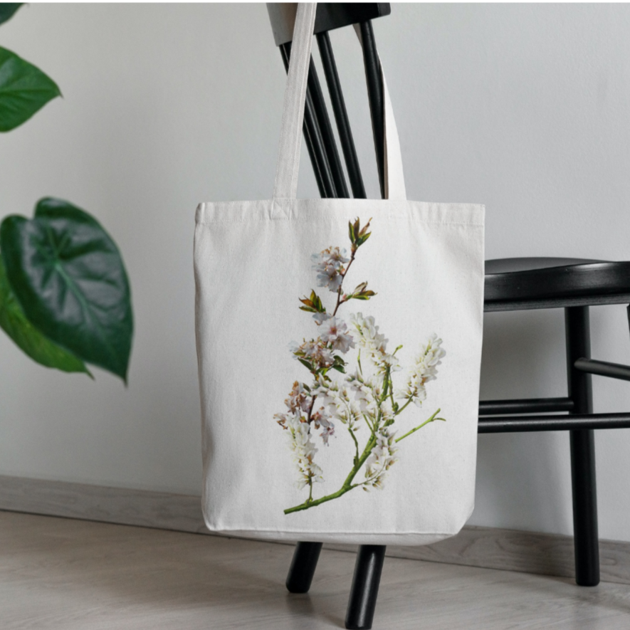 Tote bag with floral design held by a person against a neutral background