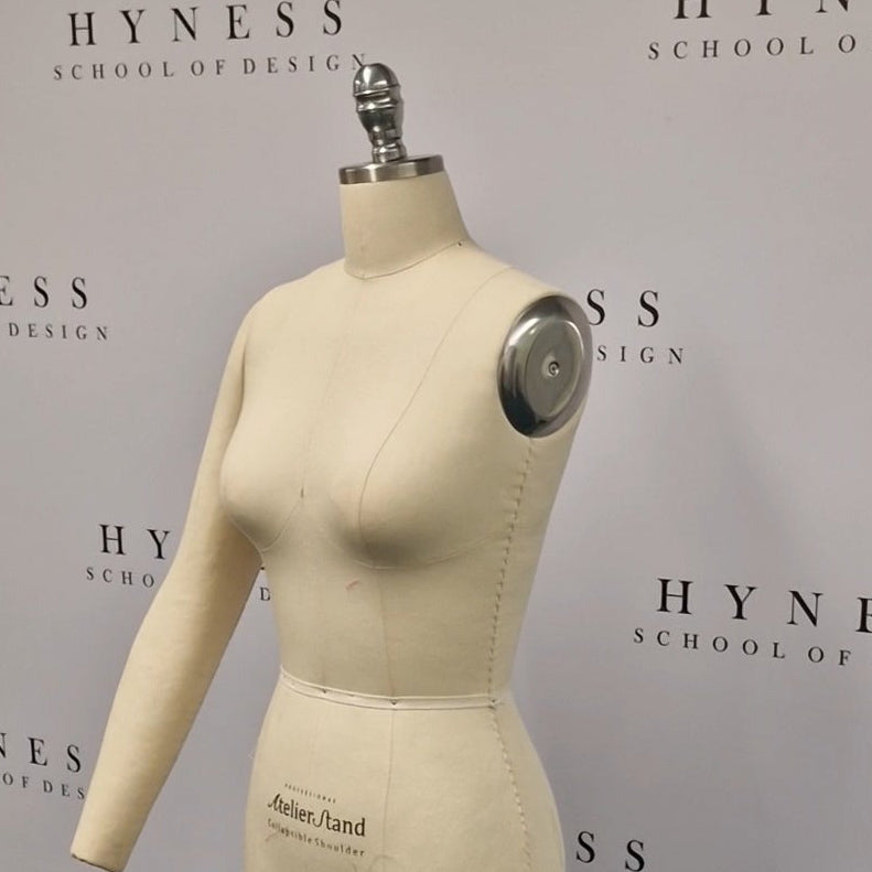Mannequin on a stand in front of a Hyness School of Design backdrop