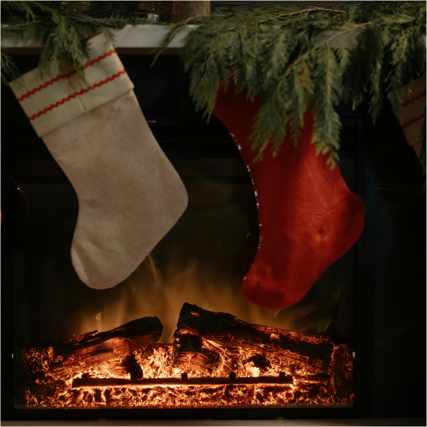 Two Christmas stockings hanging above a fireplace with logs.